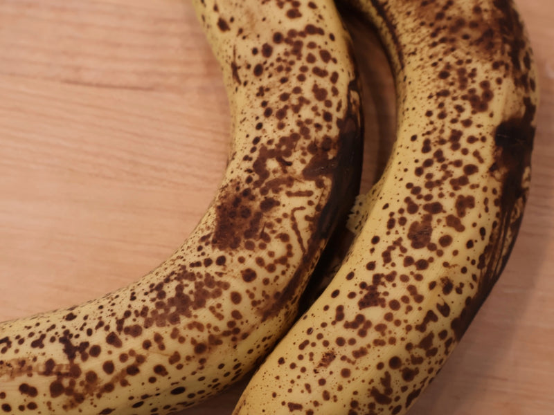 Overripe spotty bananas next to a mixing bowl of batter