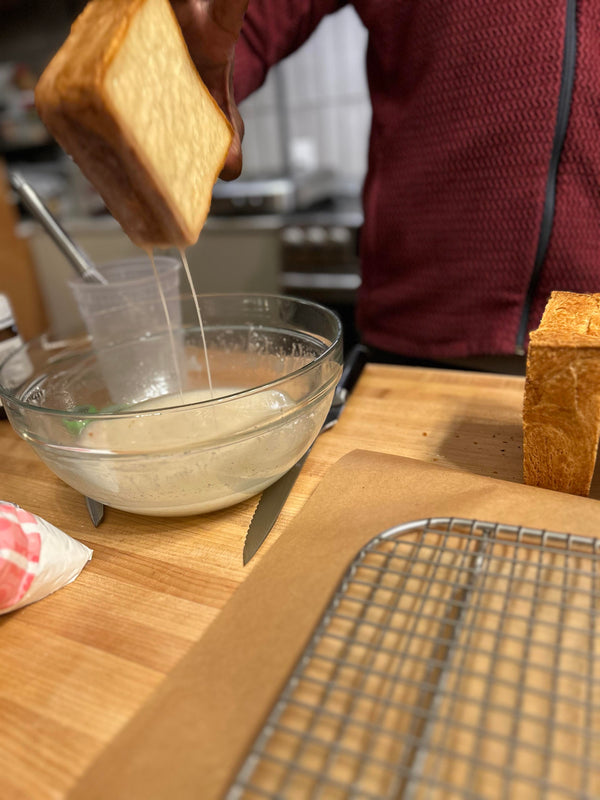 A cooled loaf over a bowl of glaze