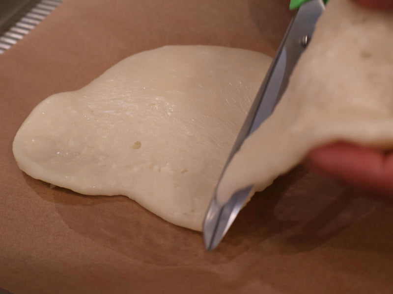 Homemade candy corn dough being worked on a parchment-covered surface