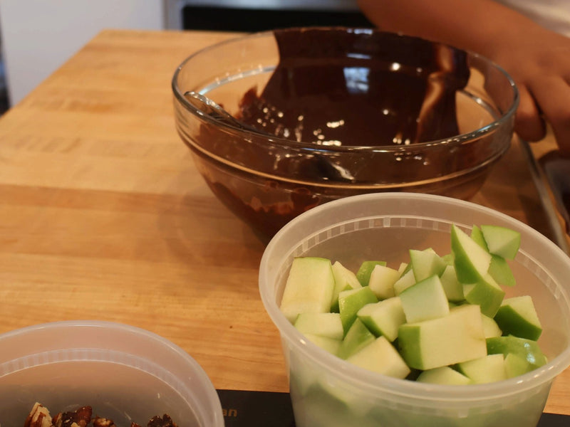 Prepared apple pieces and fall bark toppings beside melted chocolate