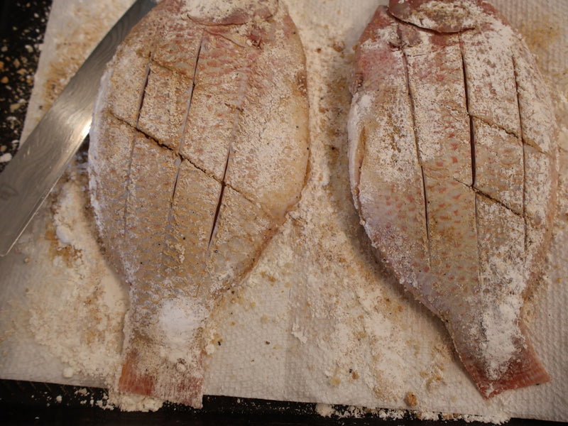 Fried fish pieces resting on a wire rack over a sheet pan