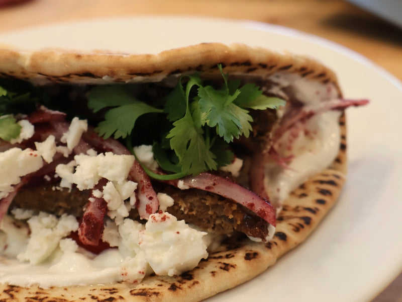 Finished oven-baked kebab flatbread with sauce, vegetables, and toppings
