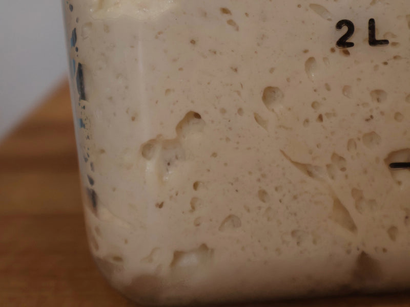 Homemade pizza dough ready for toppings on a wooden board