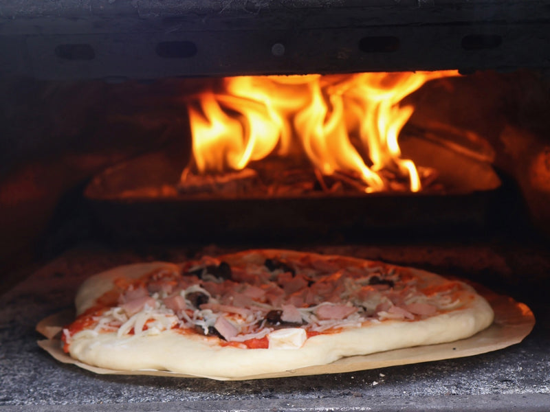 A child helping to top a homemade pizza