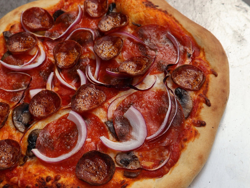 Pizza cooking in an outdoor wood-fired oven