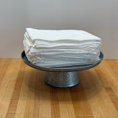 Stack of white towels on a metal stand with a wooden surface and white wall background